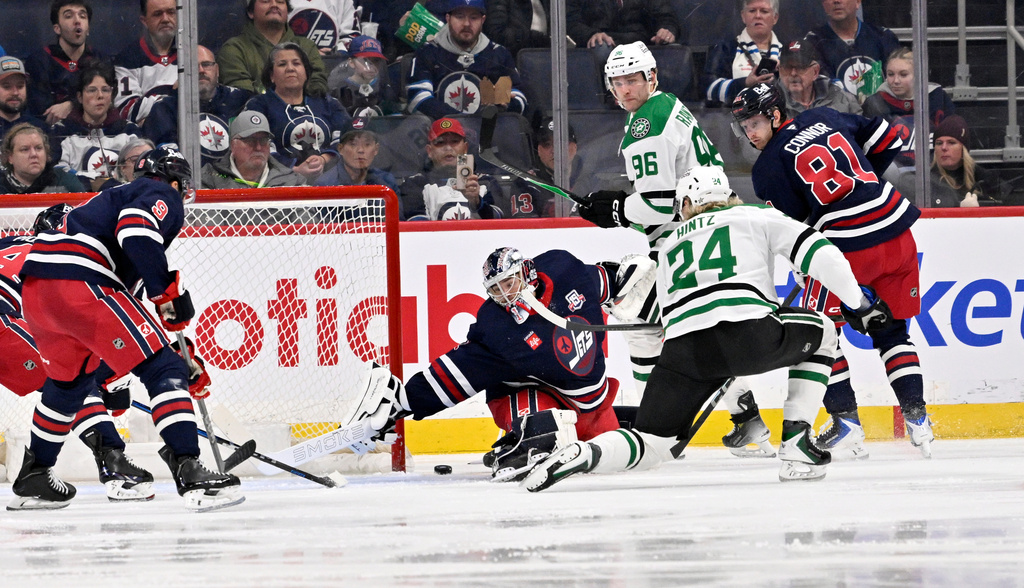 Dallas Stars' Roope Hintz (24) scores on Winnipeg Jets goaltender Eric Comrie (1) during the second period of an NHL hockey game in Winnipeg, Manitoba, Tuesday, Dec. 9, 2025. (Fred Greenslade/The Canadian Press via AP)