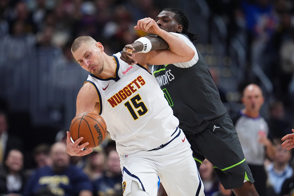 Minnesota Timberwolves center Naz Reid, right, gets called for a foul as Denver Nuggets center Nikola Jokic fields a pass in the second half in Game 1 of a first-round NBA playoffs basketball series, Saturday, April 18, 2026, in Denver. (AP Photo/David Zalubowski)