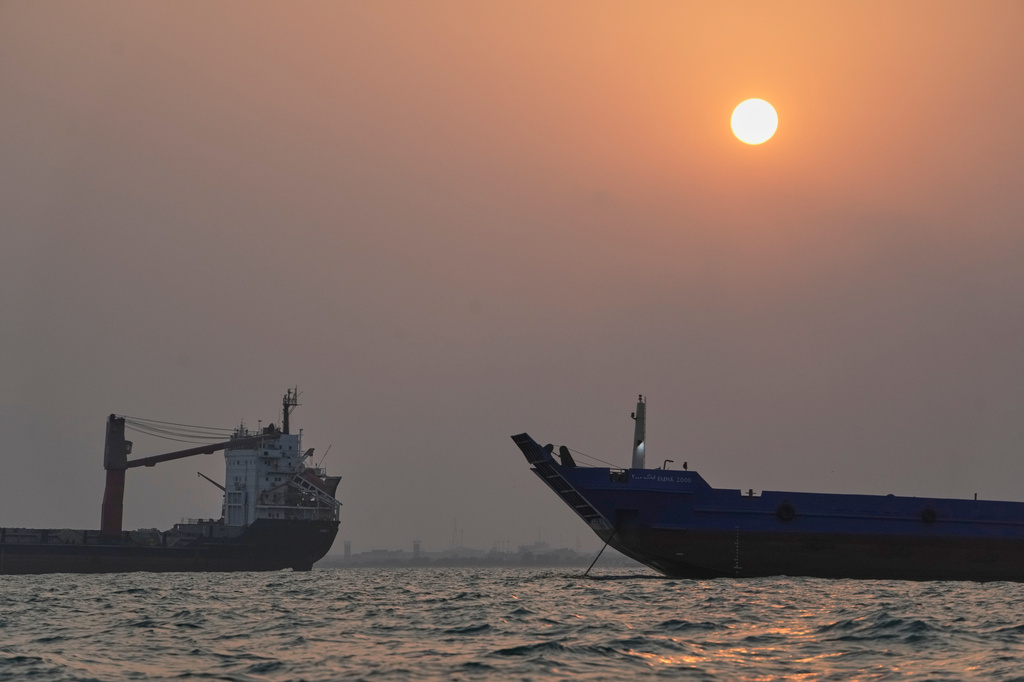 The sun sets over commercial vessels anchored in the Strait of Hormuz off Bandar Abbas, Iran, with the city's skyline in the background, Sunday, Sept. 6, 2026. (AP Photo/Vahid Salemi)