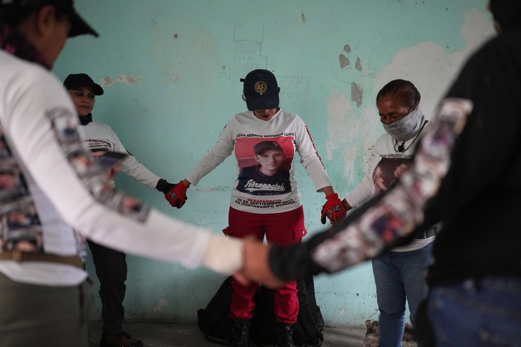 FILE - Relatives of missing people, part of a group called the Guerreros Buscadores, pray before inspecting an area where they suspect bodies may be buried, in the Valle de los Olivos neighborhood of Guadalajara, Mexico, Oct. 14, 2025. (AP Photo/Eduardo Verdugo, File)