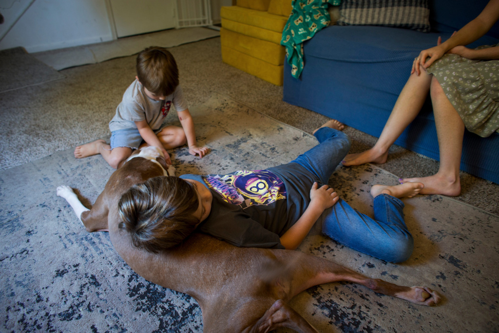 Taylor Moyer and two of her sons play with their pet dog, Roscoe, in the living room at home, Sunday, Oct. 5, 2025, in Virginia Beach, Va. (AP Photo/John Clark)
