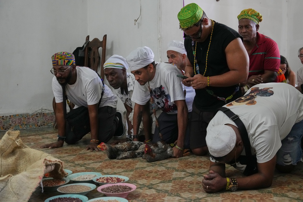 Santeria priests, also known as Babalawos, perform a cleansing ritual with roosters during a ceremony calling for peace and health in Havana, Sunday, Jan. 25, 2026. (AP Photo/Ramon Espinosa)