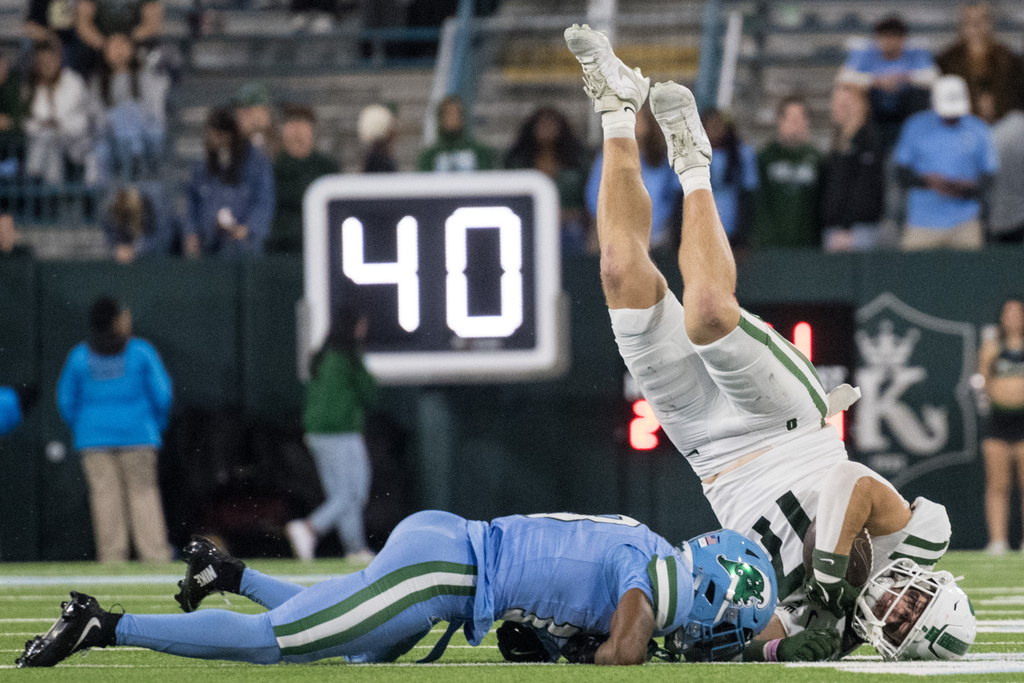 Charlotte tight end Gus McGee (17) flips after being tackled by a Tulane safety TJ Smith (13) during the second half of an NCAA college football game in New Orleans, Saturday, Nov. 29, 2025. (AP Photo/Matthew Hinton)