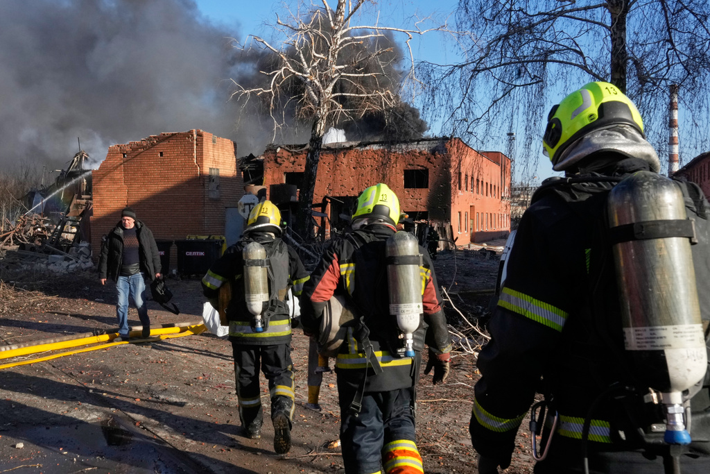 Firefighters approach the damaged railway workshops following a Russia missile and drone attack, in Brovary close to Kyiv, Ukraine, Saturday, March 14, 2026. (AP Photo/Efrem Lukatsky)