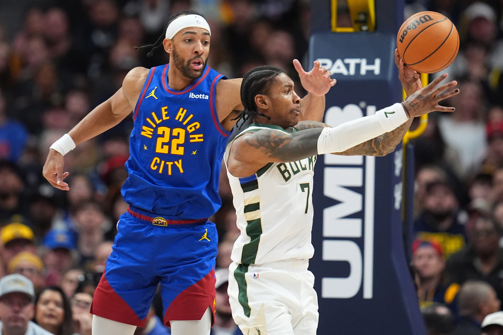Milwaukee Bucks guard Kevin Porter Jr., right, passes the ball as Denver Nuggets center Zeke Nnaji defends in the second half of an NBA basketball game, Sunday, Jan. 11, 2026, in Denver. (AP Photo/David Zalubowski)