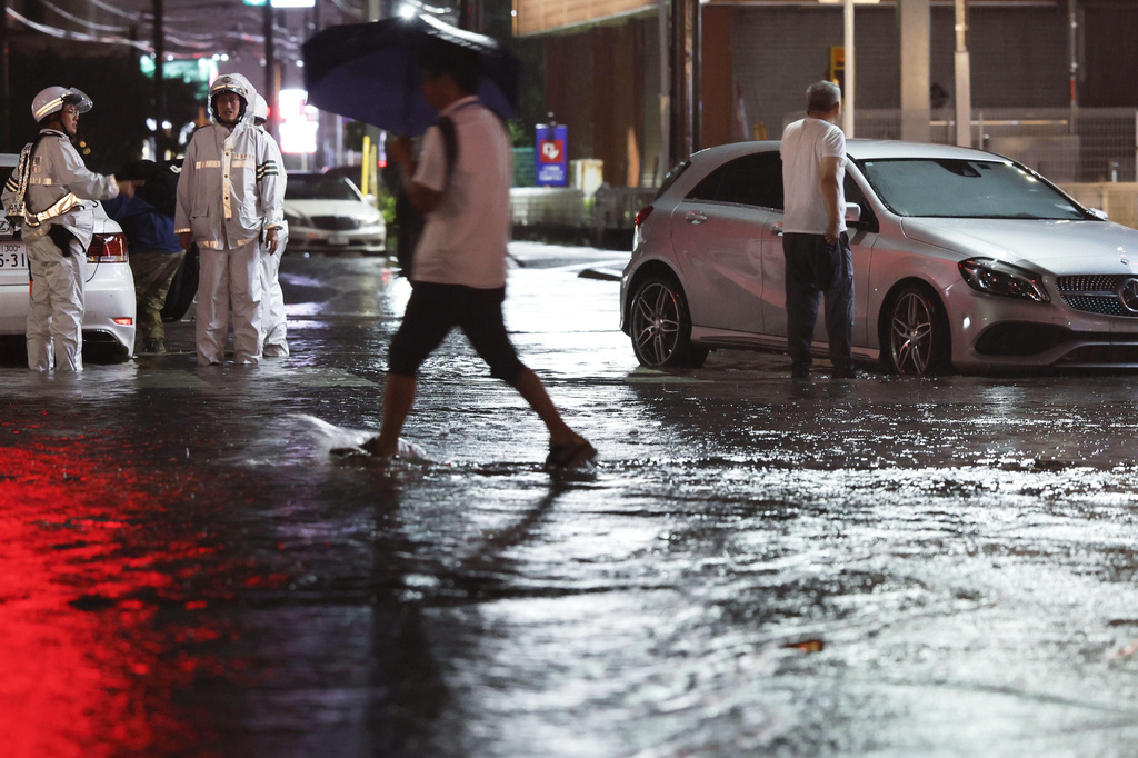 Record-breaking torrential rain floods a road, causing a car to stall, in Ichikawa, Chiba prefecture, Japan, on Thursday, Aug. 13, 2026. (Kyodo News via AP)