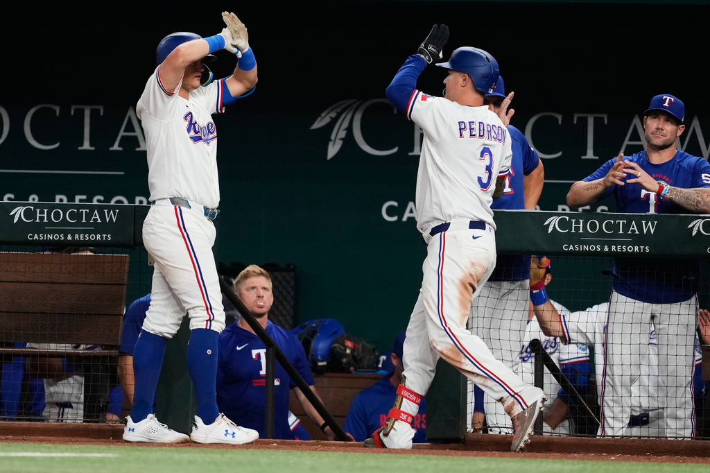 Texas Rangers' Josh Jung, left, and Joc Pederson (3) celebrate after Pederson hit a solo home run in the eighth inning of a baseball game against the Houston Astros Wednesday, May 27, 2026, in Arlington, Texas. (AP Photo/Tony Gutierrez)