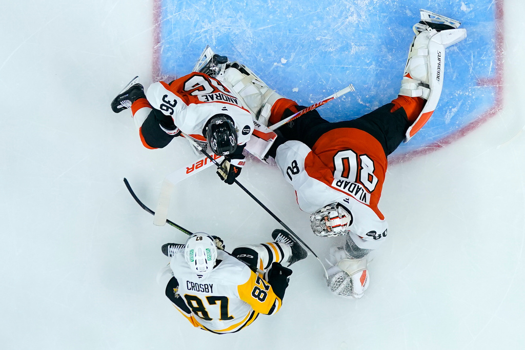 Pittsburgh Penguins' Sidney Crosby (87) scores a goal against Philadelphia Flyers' Dan Vladar (80) and Emil Andrae (36) during the first period of an NHL hockey game Monday, Dec. 1, 2025, in Philadelphia. (AP Photo/Matt Slocum)
