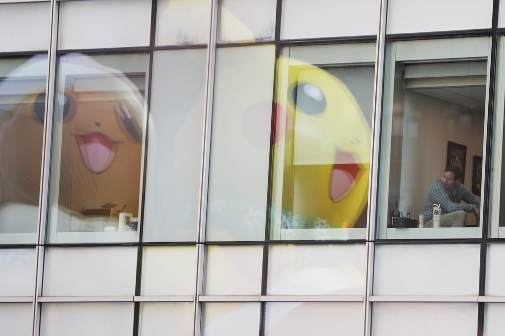 People inside office buildings watch as the Pikachu balloon passes during the Macy's Thanksgiving Day Parade, Thursday, Nov. 27, 2025, in New York. (AP Photo/Heather Khalifa)