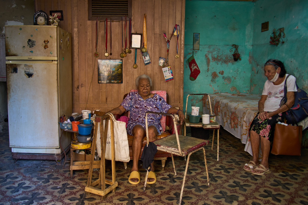 Mercedes Lopez Rey, 83, right, visits with her friend Julia Barcelo, 83, who is recovering from breast cancer treatment, after bringing her a meal from a church-sponsored program, in Old Havana. Cuba, Friday, April 10, 2026. (AP Photo/Ramon Espinosa)