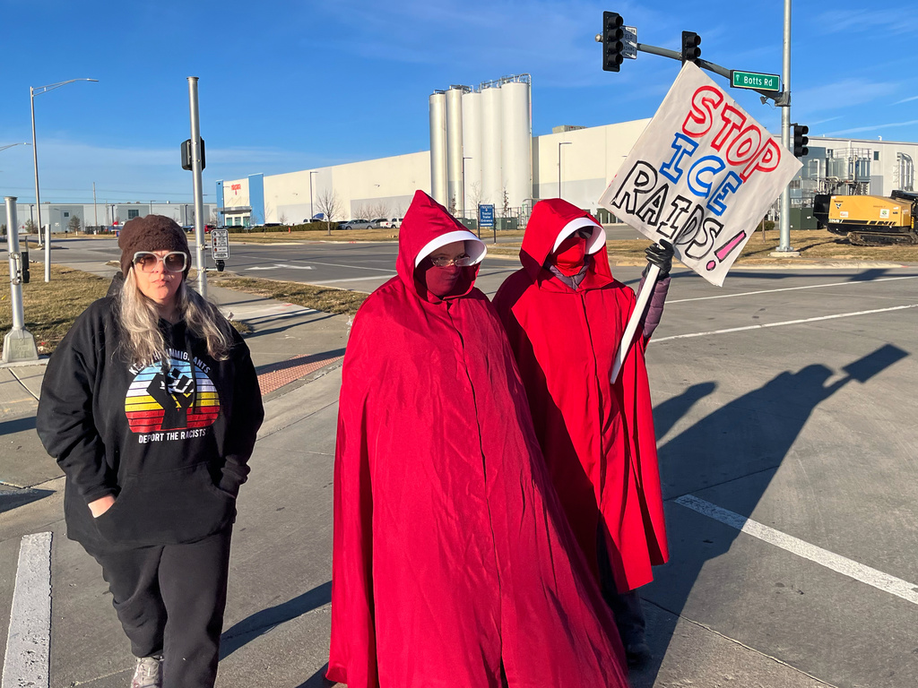 Melissa Kane, a self-described worried mother, joins protestors clad in red cloaks inspired by the dystopian novel and TV series, "The Handmaid's Tale," as they protest outside a warehouse federal officials are touring to consider repurposing for an ICE detention facility, in Kansas City, Mo., Thursday, Jan. 15, 2026. (AP Photo/Heather Hollingsworth)