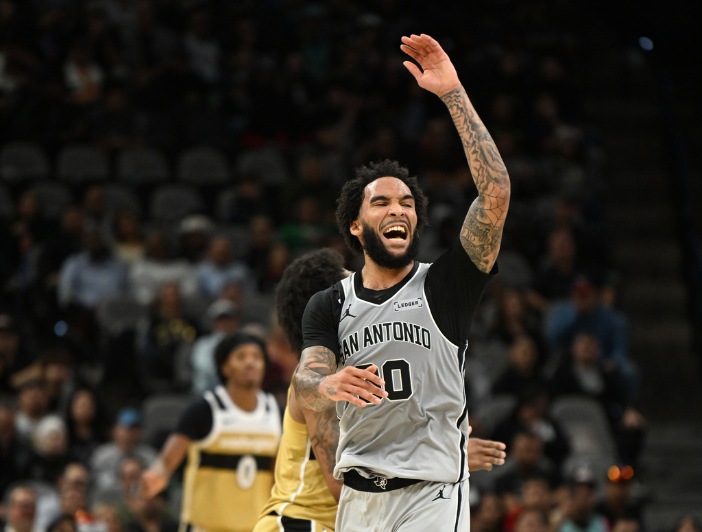 San Antonio Spurs forward Julian Champagnie, foreground, reacts as his team pulls away against the Washington Wizards during the second half of an NBA basketball game in San Antonio, Thursday, Dec. 18, 2025. (AP Photo/Billy Calzada)