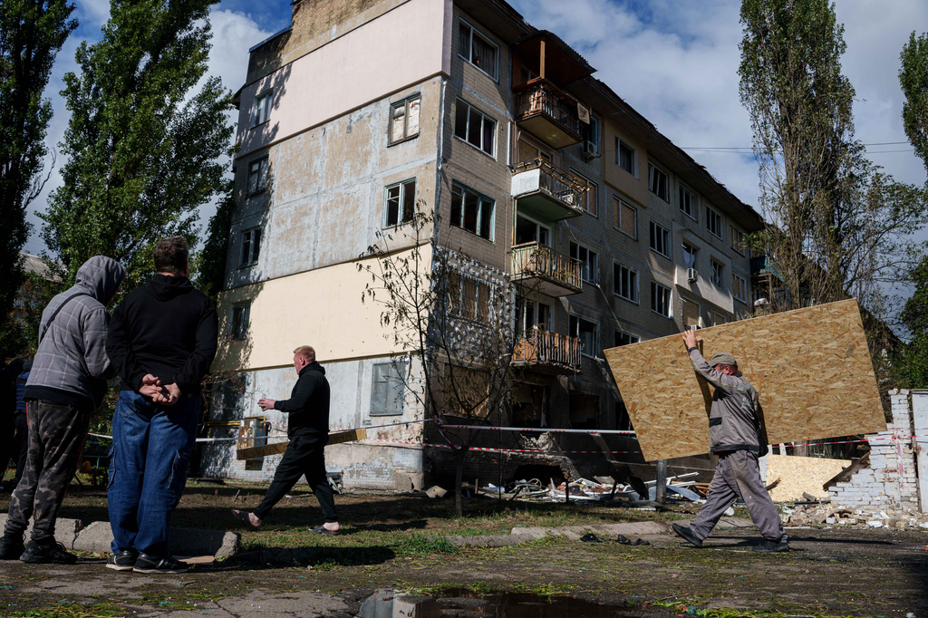 A municipal worker carries plywood to board up windows of an apartment building damaged by a Russian drone strike in Kyiv, Ukraine, Tuesday, Sept. 22, 2026. (AP Photo/Evgeniy Maloletka)