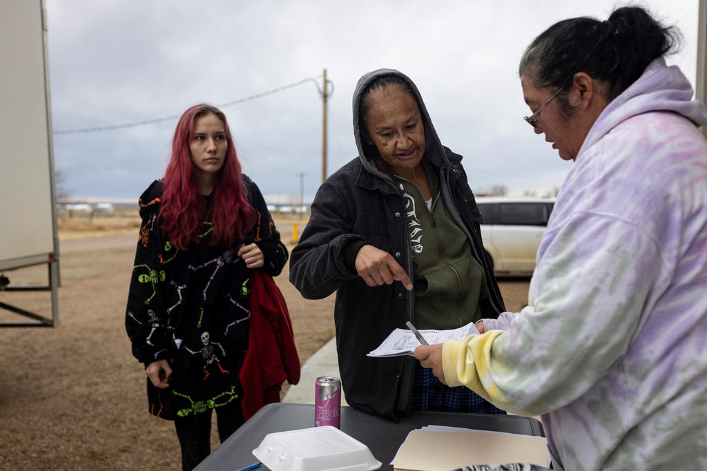 Carrie Shawl, center, and Natalie Cooper, left, show their SNAP documents at a food distribution site in Frazer, Mont., on Monday, Nov. 10, 2025. (AP Photo/Mike Clark)