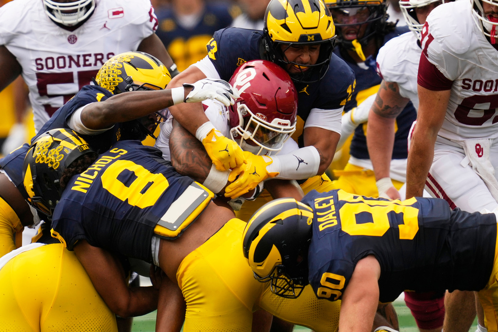 Oklahoma running back Xavier Robinson (21) is stopped by Michigan defensive end Dominic Nichols (8) in the first half of an NCAA college football game Saturday, Sept. 12, 2026, in Ann Arbor, Mich. (AP Photo/Paul Sancya)