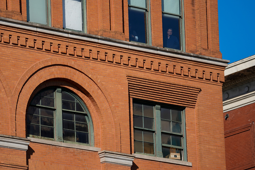 FILE - People stand at windows one floor above the 6th floor of the book depository at Dealey Plaza, on the 60th anniversary of former President John F. Kennedy's assassination, Nov. 22, 2023, in Dallas. (AP Photo/Julio Cortez, File)