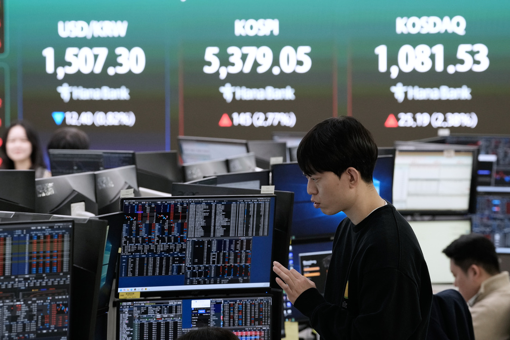 A currency trader works near a screen showing the Korea Composite Stock Price Index (KOSPI), top center, and the foreign exchange rate between U.S. dollar and South Korean won, top center left, at the foreign exchange dealing room of the Hana Bank headquarters in Seoul, South Korea, Friday, April 3, 2026. (AP Photo/Ahn Young-joon)