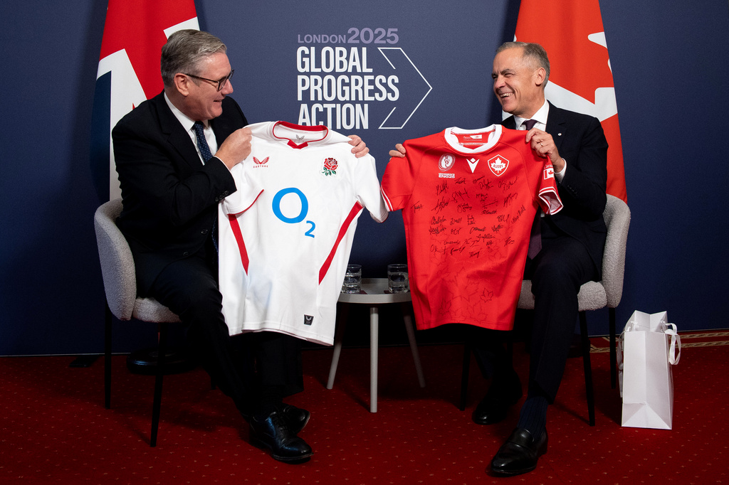 Britain's Prime Minister Keir Starmer, left, and Canada's Prime Minister Mark Carney react as they trade their nations rugby shirts ahead of the Women's Rugby World Cup Final between Canada and England, during a bilateral meeting on the sidelines of the 2025 Global Progress Action Summit in central London, Friday Sept. 26, 2025. (Niklas Halle'n/Pool Photo via AP)