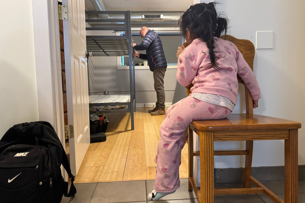A child whose family is being sought by federal immigration agents watches as a volunteer prepares a bunk bed for her family at a Minneapolis safe house Friday, Jan. 16, 2026. (AP Photo/Jack Brook)