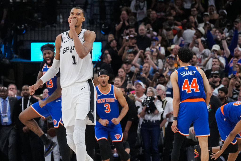 San Antonio Spurs forward Victor Wembanyama walks off the court as time expires during the second half of Game 2 of the NBA Finals basketball series as New York Knicks guard Landry Shamet (44), guard Josh Hart (3), and center Mitchell Robinson (23) celebrate, Friday, June 5, 2026, in San Antonio. (AP Photo/Eric Gay)