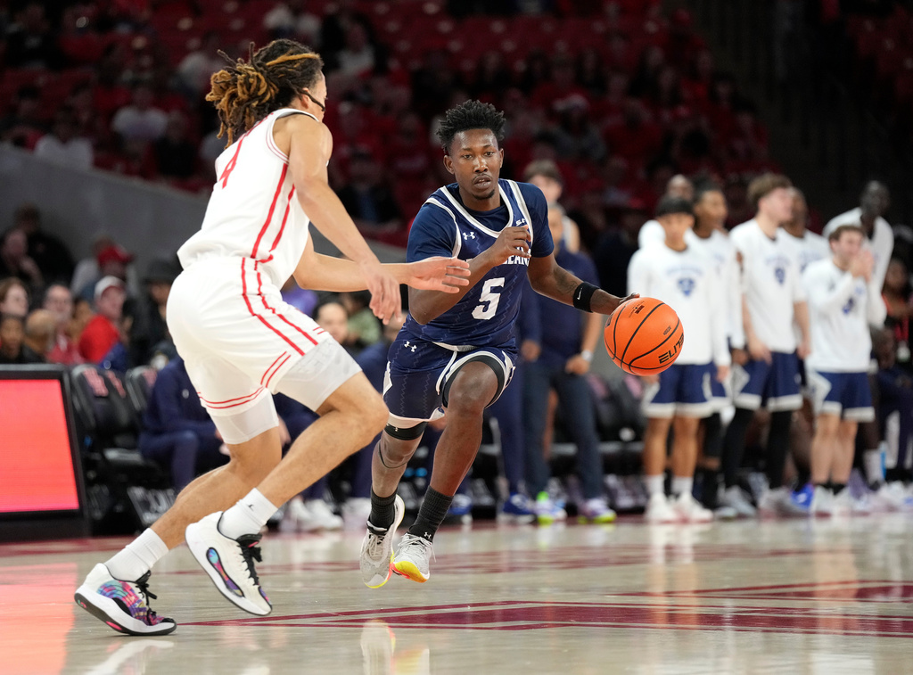 New Orleans guard Jakevion Buckley (5) runs the ball against Houston guard Kingston Flemings, left, during the first half of an NCAA college basketball game, Saturday, Dec. 13, 2025, in Houston. (AP Photo/Karen Warren)