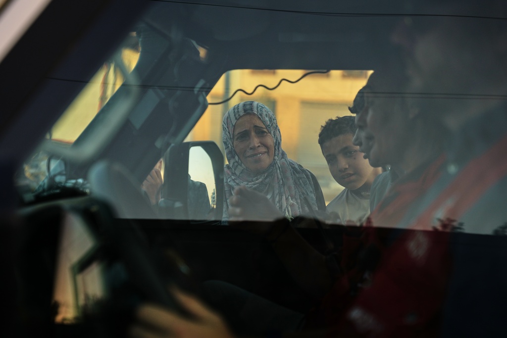 A woman and a boy look into a Red Cross vehicle carrying the bodies of two people believed to be deceased hostages handed over by Hamas, before it continues toward the Kissufim border crossing with Israel to transfer the remains to Israeli authorities, in Deir al-Balah, central Gaza Strip, Thursday, Oct. 30, 2025. (AP Photo/Abdel Kareem Hana)