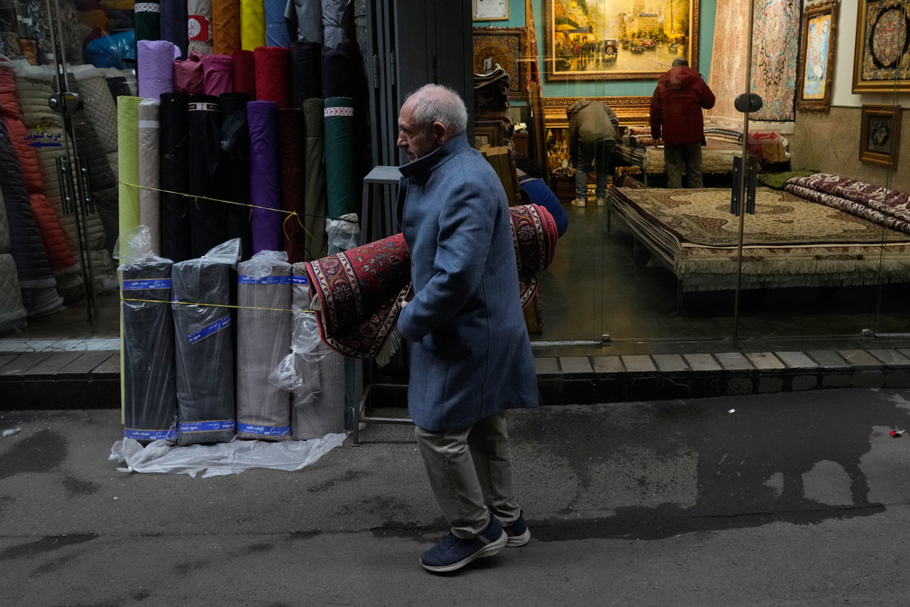 A man carries a carpet at Tehran's historic Grand Bazaar, Tuesday, Jan. 20, 2026, in Iran. (AP Photo/Vahid Salemi)