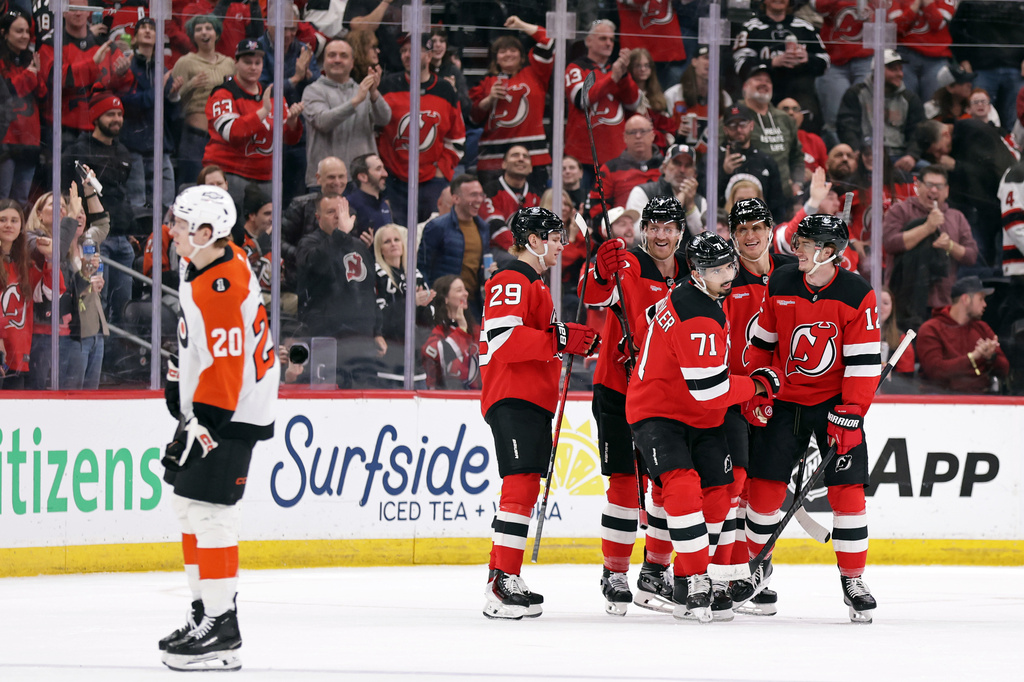 New Jersey Devils center Cody Glass (12) is congratulated by teammates after scoring a goal during the first period of an NHL hockey game against the Philadelphia Flyers, Tuesday, April 7, 2026, in Newark, N.J. (AP Photo/Adam Hunger)