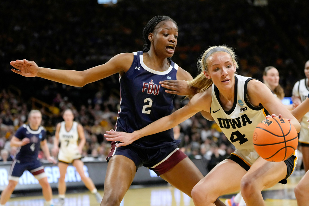 Iowa guard Kylie Feuerbach (4) drives past Fairleigh Dickinson forward Akeelah Lafleur (2) during the first half in the first round of the NCAA college basketball tournament, Saturday, March 21, 2026, in Iowa City, Iowa. (AP Photo/Charlie Neibergall)