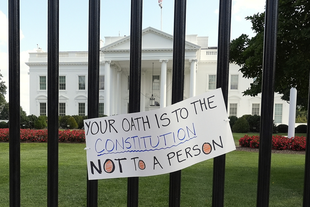 A sign hangs outside the White House as activists protest President Donald Trump's federal takeover of policing of the District of Columbia, Saturday, Aug. 16, 2025, in Washington. (AP Photo/Alex Brandon)