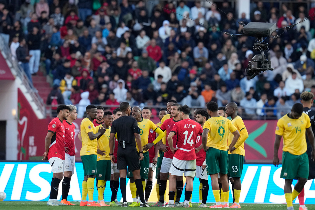 Players gather around the referee Pacifique Ndabihawenimana while a penalty kick check is being conducted during the Africa Cup of Nations group B soccer match between Egypt and South Africa in Agadir, Morocco, Friday, Dec. 26, 2025. (AP Photo/Themba Hadebe)