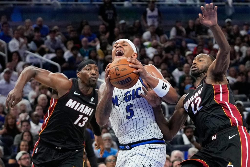 Orlando Magic forward Paolo Banchero (5) gets off a shot as he moves betweernMiami Heat center Bam Adebayo (13) and forward Andrew Wiggins (22) during the second half of an NBA basketball game, Wednesday, Oct. 22, 2025, in Orlando, Fla. (AP Photo/John Raoux)