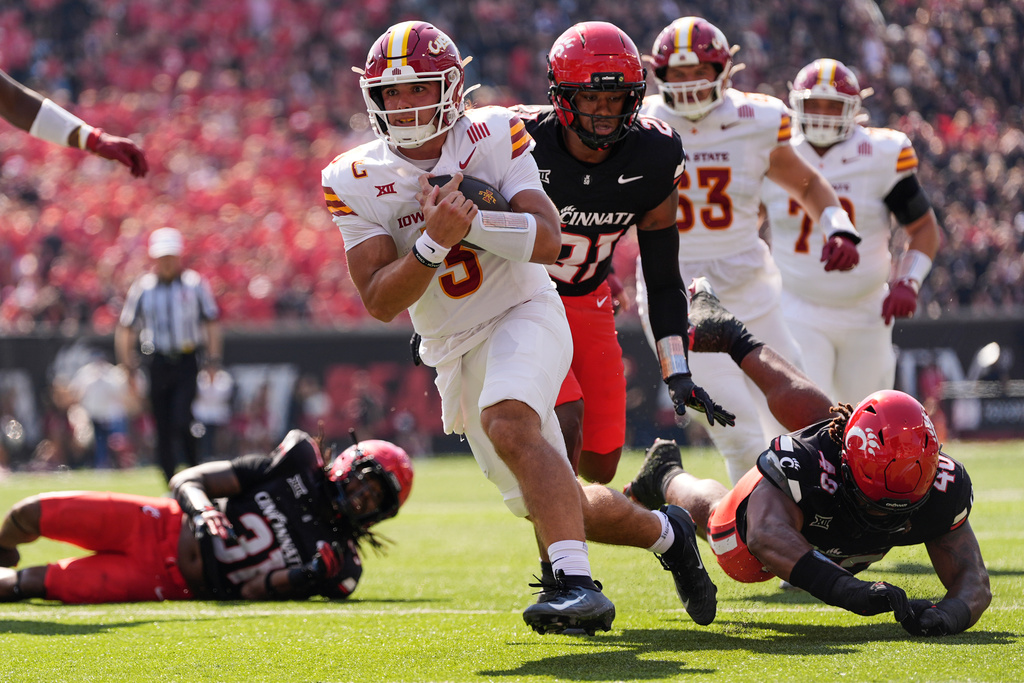 Iowa State quarterback Rocco Becht, (3) runs for a touchdown ahead of Cincinnati defensive linemen C.J. McCray (21) and Kamari Burns (40) during the first half of an NCAA college football game, Saturday, Oct. 4, 2025, in Cincinnati. (AP Photo/Carolyn Kaster)