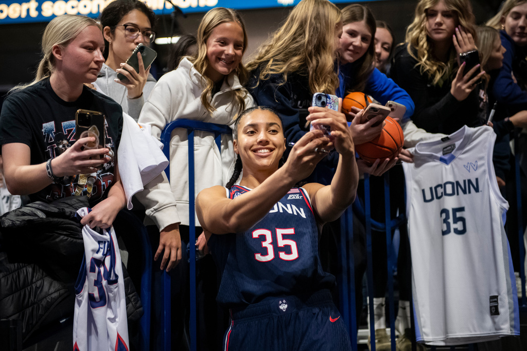 UConn Huskies guard Azzi Fudd (35) takes a selfie with a fan after beating Xavier during a NCAA college basketball game Sunday, Nov. 30, 2025, in Cincinnati. (AP Photo/Tanner Pearson)