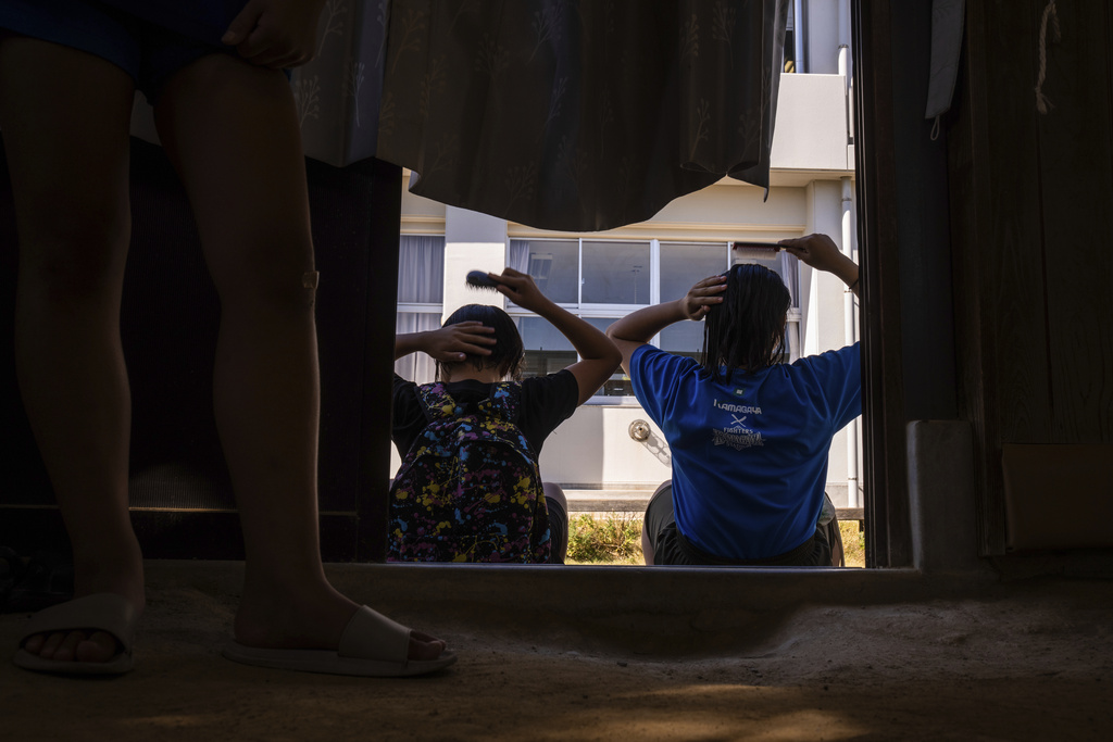 Wrestlers comb their hair after a practice session at a sumo camp in Tottori Johoku High School in Tottori, Japan, on July 28, 2025. (AP Photo/Louise Delmotte)