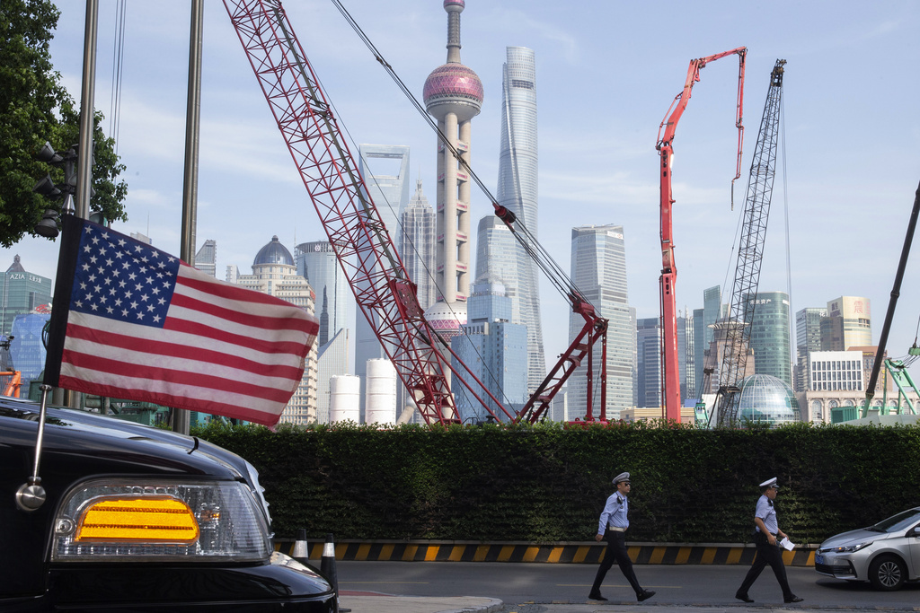 HOLD FOR STORY CHINA US CHAMBER FILE - Chinese traffic police officers walk by a U.S. flag on an embassy car outside a hotel in Shanghai where officials from both sides met for talks aimed at ending a tariff war on July 30, 2019. (AP Photo/Ng Han Guan, File)