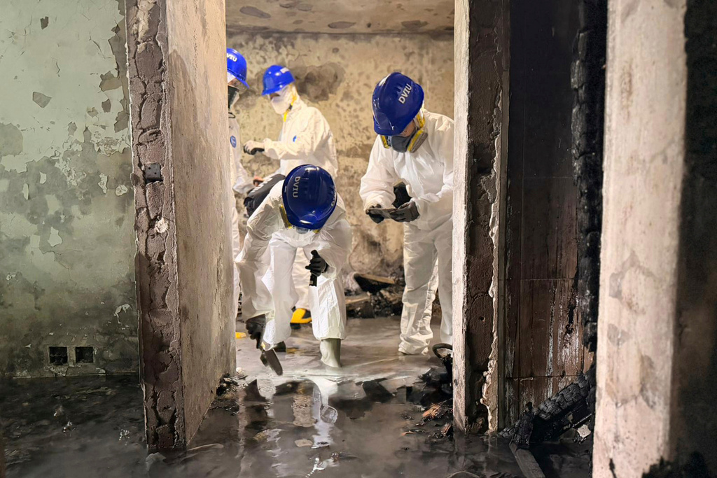 In this photo released by Hong Kong Police Public Relations Branch, members of the Disaster Victim Identification Unit work in an apartment in the aftermath of a deadly Wednesday fire at Wang Fuk Court, a residential estate in the Tai Po district of Hong Kong's New Territories Sunday, Nov. 30, 2025. (Hong Kong Police Public Relations Branch via AP)