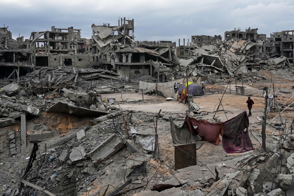 Displaced Palestinians set up their tents amid destroyed buildings at the Shati refugee camp in Gaza City, Sunday, Oct. 12, 2025, after Israel and Hamas agreed to a pause in their war and the release of the remaining hostages. (AP Photo/Abdel Kareem Hana)