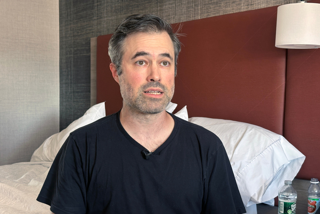 Mark Bray, a Rutgers assistant professor of history, waits in a hotel room in Newark, N.J., before a planned flight to Spain on Thursday, Oct. 9, 2025. (AP Photo/Ted Shaffrey)