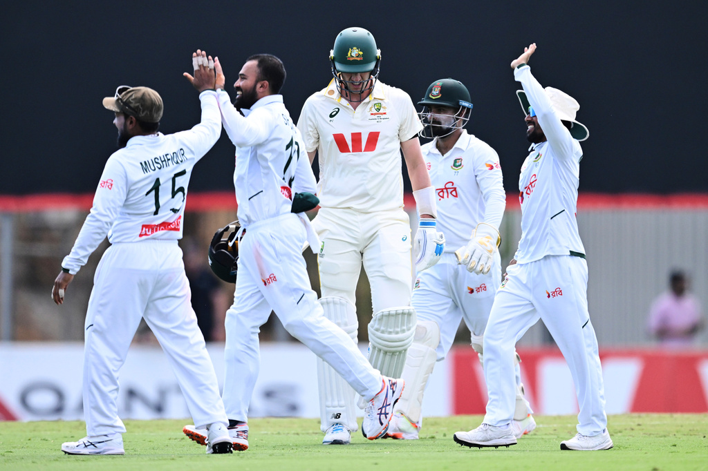Pat Cummins, center, of Australia walks from the field after being dismissed by Mehidy Hasan Miraz, second left, of Bangladesh during play on day four of the first cricket test in Darwin, Australia, Sunday, Aug. 16, 2026. (James Ross/AAP Image via AP)