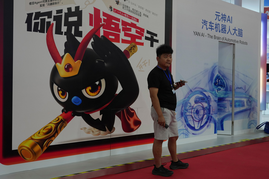 A man stands near a poster promoting the AI agent from Alibaba at the China International Supply Chain Expo in Beijing on Monday, June 22, 2026. (AP Photo/Ng Han Guan)