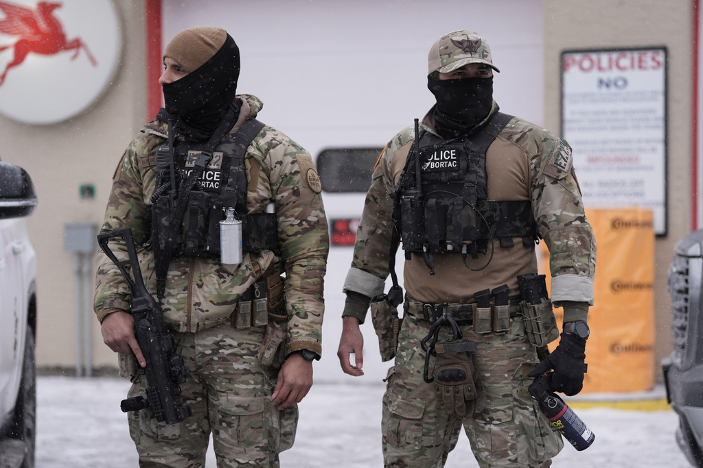 Federal agents stand outside a convenience store on Wednesday, Jan. 21, 2026, in Minneapolis. (AP Photo/Angelina Katsanis)