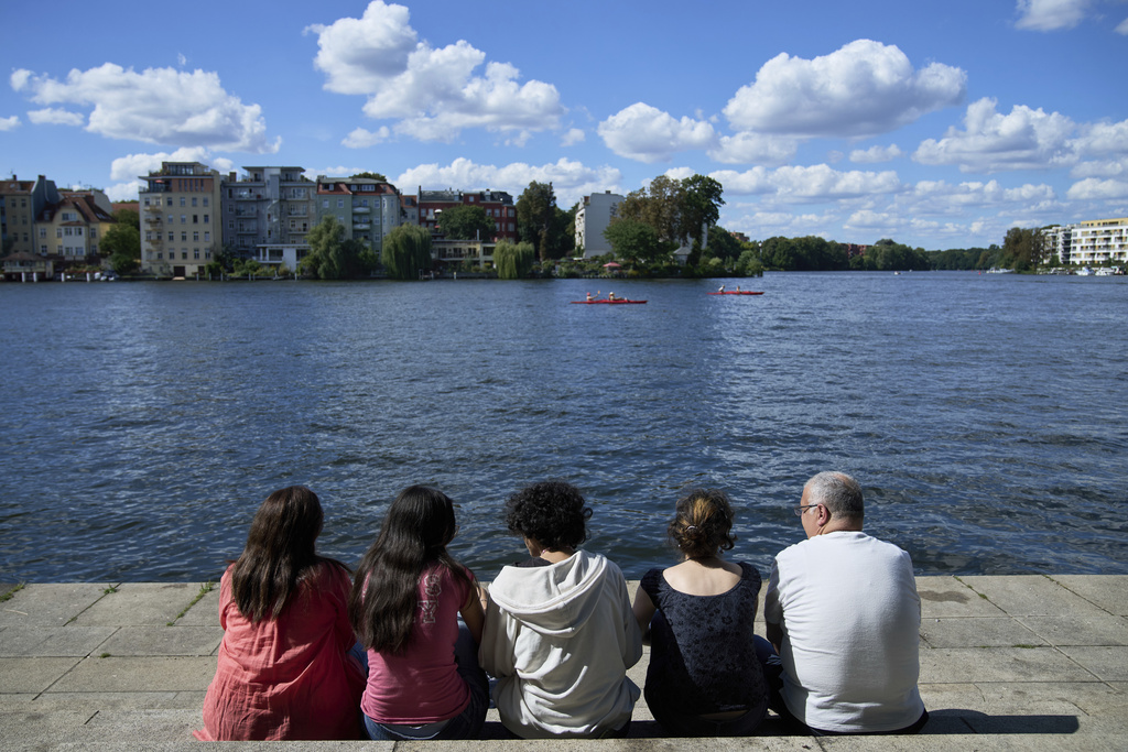 The Wahbeh family, who immigrated to Germany from Syria, sits along a river in Berlin on Aug. 31, 2025. (AP Photo/Ebrahim Noroozi)