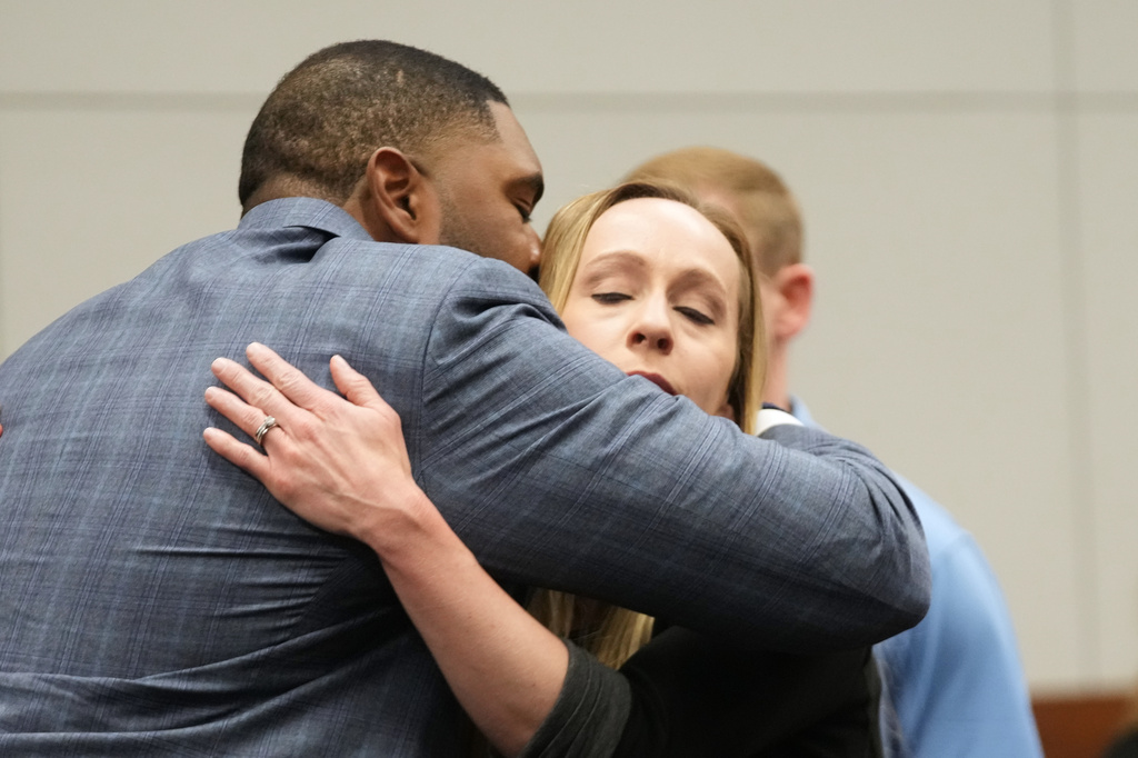 Former Michigan football coach Sherrone Moore hugs his wife wife Kelli Moore in court Tuesday, April 14, 2026, in Ann Arbor, Mich. (AP Photo/Paul Sancya)