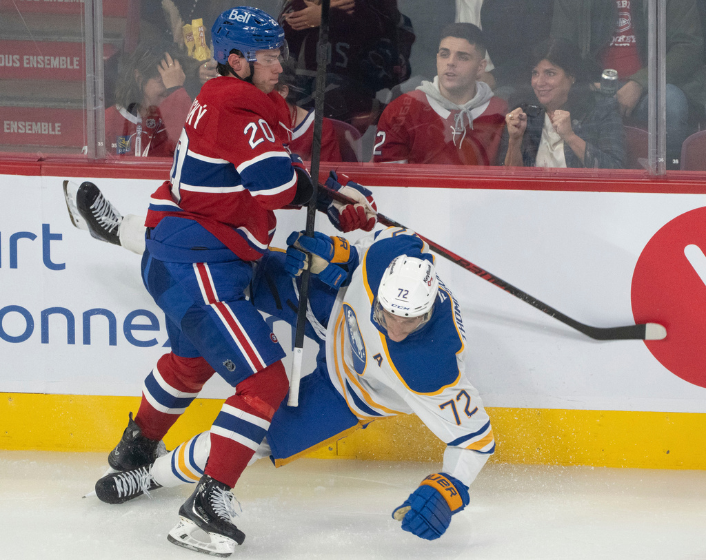 Buffalo Sabres' Tage Thompson (72) is checked into the boards by Montreal Canadiens' Juraj Slafkovský (20) during second period NHL hockey action in Montreal on Monday, Oct. 20, 2025. (Christinne Muschi/The Canadian Press via AP)