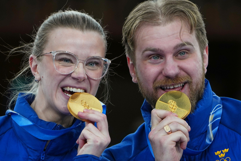 Sweden's Isabella Wranaa and Rasmus Wranaa celebrate on the podium after winning the gold medal match of the mixed doubles curling at the 2026 Winter Olympics, in Cortina d'Ampezzo, Italy, Tuesday, Feb. 10, 2026. (AP Photo/Misper Apawu)