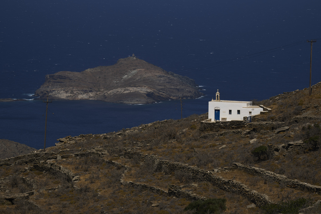 A family-owned chapel on the island of Tinos, Greece, with the isle of Planitis in the background, is seen on Saturday, Sept. 6, 2025. (AP Photo/Petros Giannakouris)