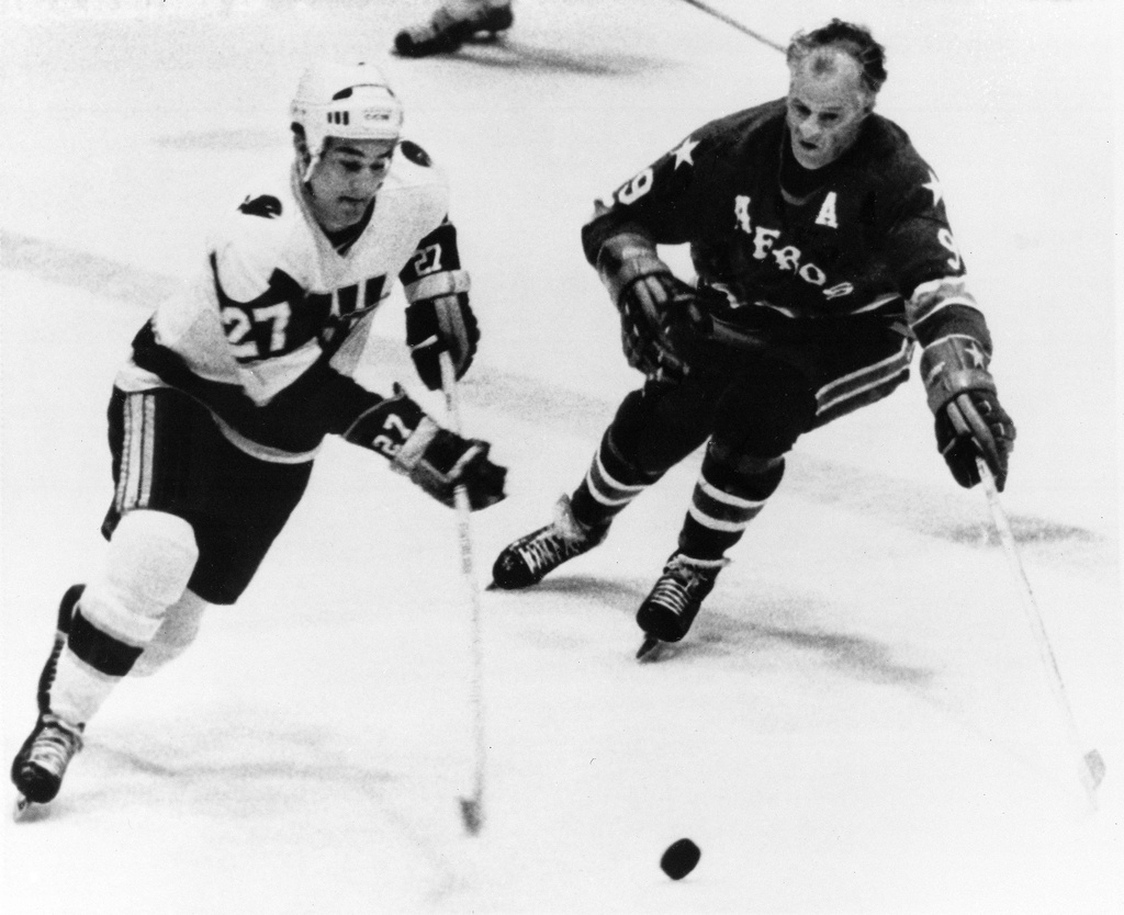 FILE - Gordie Howe, right, of the Houston Aeros, comes in to head Tom Earl of the New England Whalers off rom the puck during the first period of the World Hockey Association playoff game in Hartford, Conn., May 11, 1976. (AP Photo/Bob Child, File)