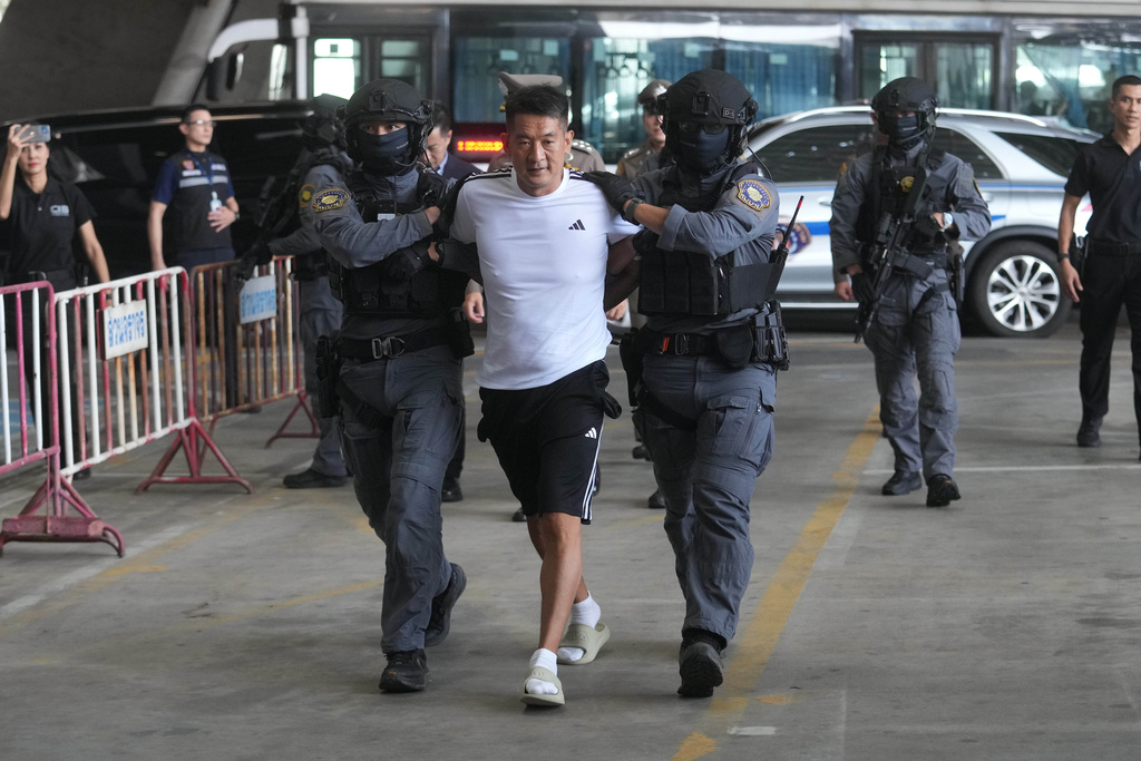 She Zhijiang, an alleged transnational crime kingpin accused by Beijing of having run illegal online gambling operations, is escorted by police at Suvarnabhumi International Airport in Thailand's Samut Prakarn province ahead of being extradited to China, Wednesday, Nov. 12, 2025. (AP Photo/Sakchai Lalit)