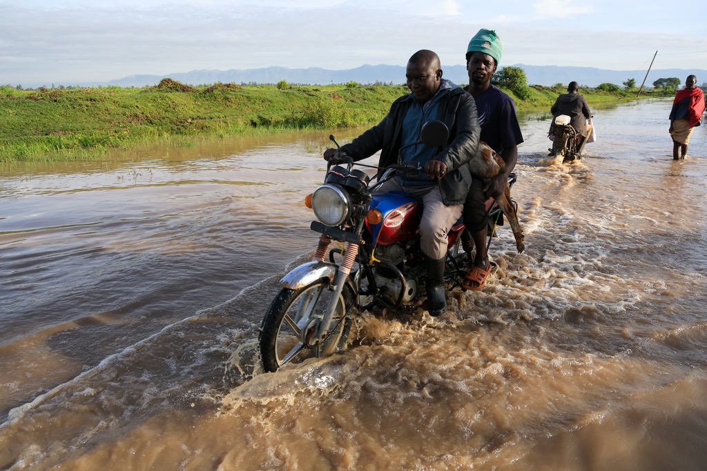 People ride through flood waters following heavy rains in Ahero, Western Kenya, Tuesday, March 24, 2026. (AP Photo/Andrew Kasuku)
